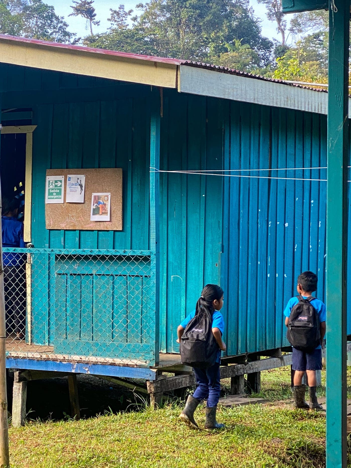 Children with backpacks outside a blue rural house along the trail